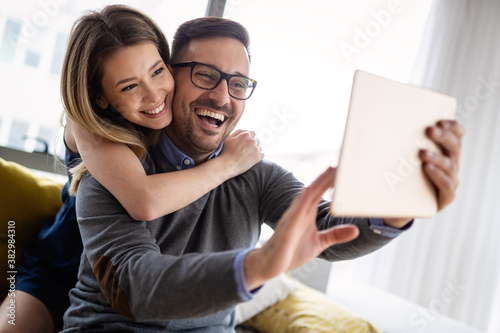 Happy couple in love having fun with digital tablet