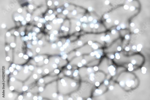 Christmas lights on grey background, blurred view
