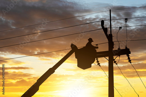 silhouette electrician works on cable car to maintain high voltage transmission lines.