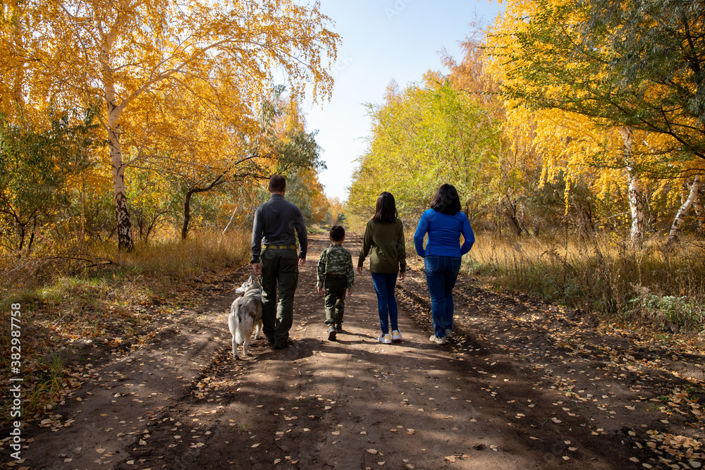 Fototapeta premium Family walk in the yellow woods with a dog.