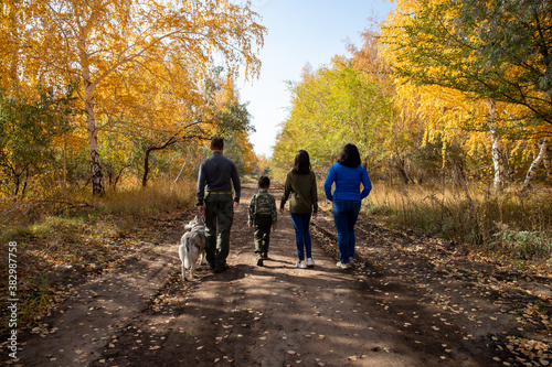 Family walk in the yellow woods with a dog. © Kira0Kirina