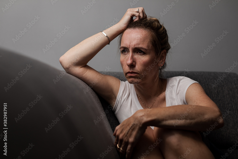 Depressed mid-aged woman at home feeling sad, lonely, anxious (color toned image)