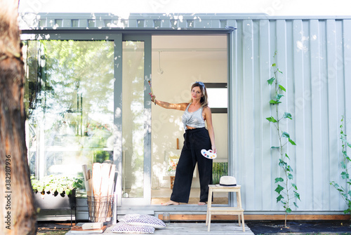 Portrait of mature woman with pallete painting in container house. photo