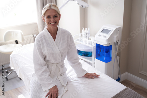 Happy beautiful woman wearing white bathrobe in spa
