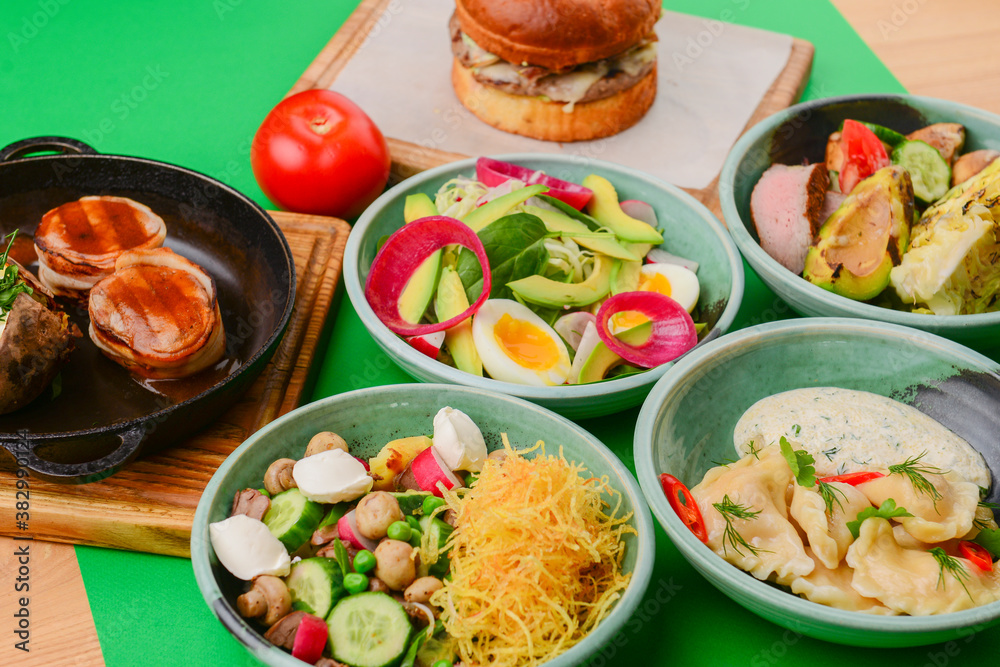 Variety of food dishes on bright green background. Table covere with food flat lay, top view, frame. Variety of food dishes on bright green background. Table covere with food flat lay, top view, frame.