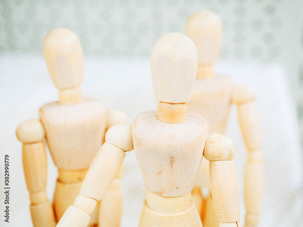 A figurine of a wooden man on hinges against the background of two other figures. Photo with focus in the foreground A figurine of a wooden man on hinges against the background of two other figures. Photo with focus in the foreground