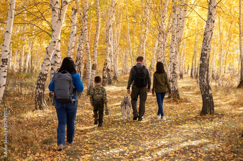 Family walk in the yellow woods with a dog.