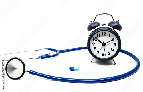 Stethoscope, clock and blue capsule medicine on the white background. A medical concept for pharmacokinteics. The importance of accurate dosage.