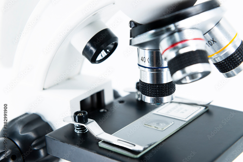 Close-up of microscope lens on the white background. A basic instrument for research, science and biology. Close-up of microscope lens on the white background. A basic instrument for research, science and biology.