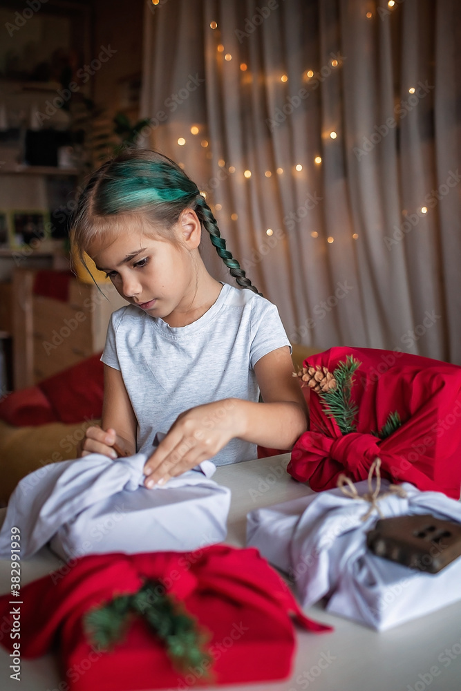 Zero waste Christmas. Cute girl learning to wrap gifts in traditional Japanese style furoshiki