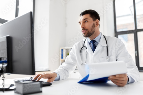 healthcare, medicine and people concept - male doctor with computer working at hospital