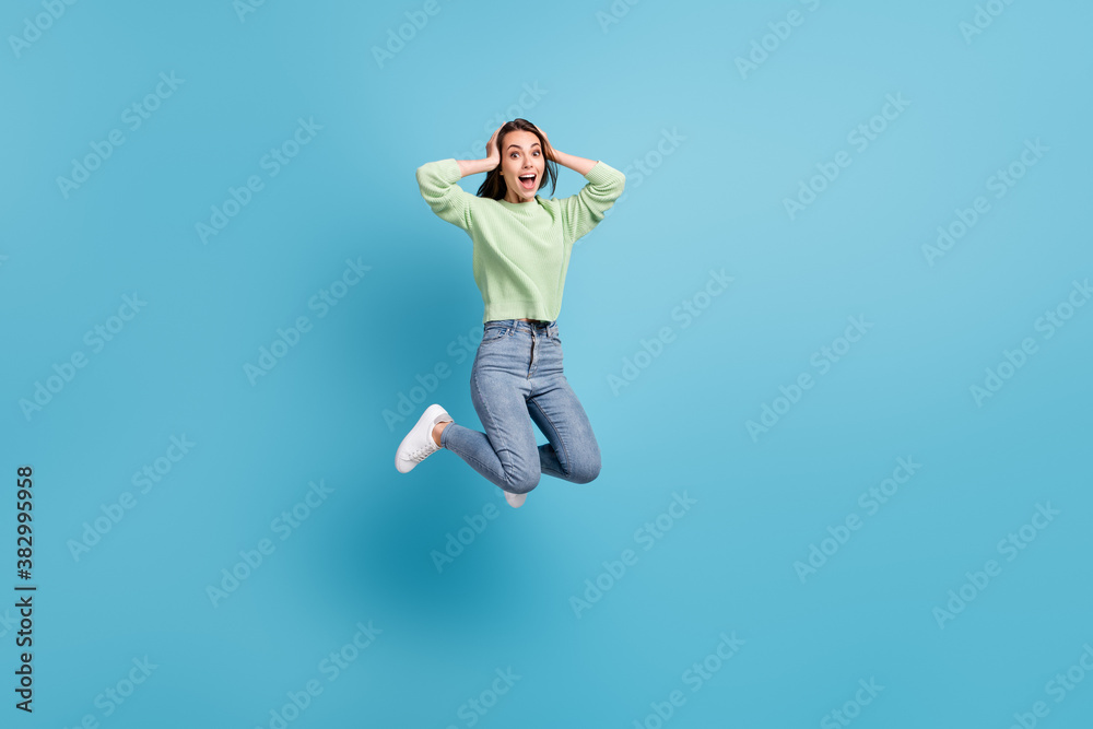 Full length body size photo of impressed amazed shocked female student jumping up holding hands on head isolated on vivid blue color background