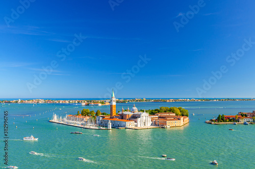 Aerial panoramic view of San Giorgio Maggiore island with Campanile San Giorgio in Venetian Lagoon, sailing boats in St. Mark Basin, Lido island, blue sky background, Venice city, Veneto region, Italy