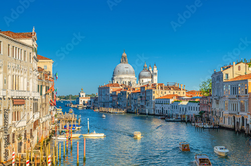 Venice cityscape with Grand Canal waterway. Gondolas and boats docked and sailing Canal Grande. Santa Maria della Salute Roman Catholic church on Punta della Dogana. Veneto Region, Italy. © Aliaksandr