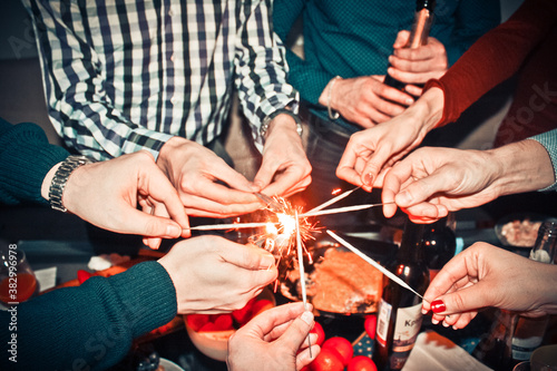 Winter holidays and people concept - happy friends with sparklers celebrate Christmas at home holiday