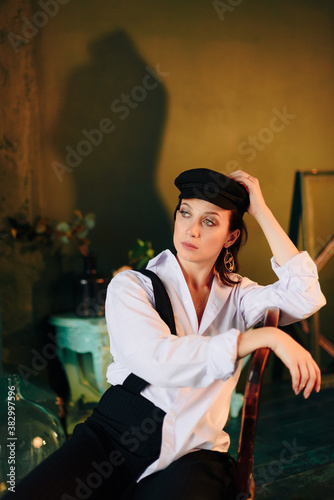 Portrait of a beautiful young woman in a white shirt and black trousers at home