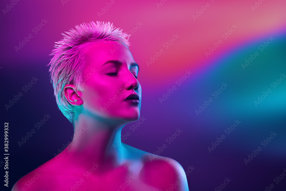 Dream. Portrait of female fashion model in neon light on dark studio background. Beautiful caucasian woman with trendy make-up and well-kept skin. Vivid style, beauty concept. Close up. Copyspace