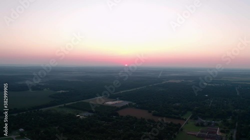Aerial view of the sunrise or sunset over a rural community and farmland with fog in the air