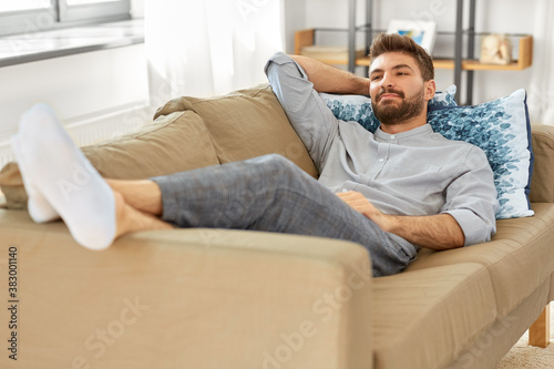 people and leisure concept - young man sitting on sofa at home