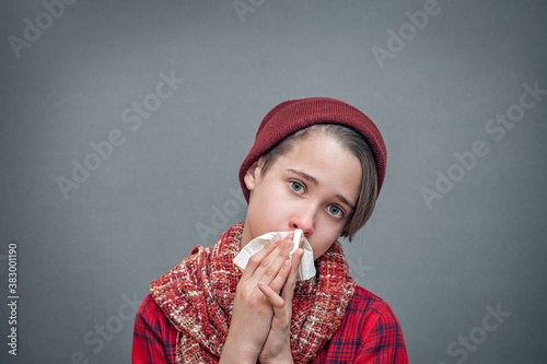 runny nose, snot in the nose, boy with red nose and handkerchief in his hands, blowing his nose, flu symptoms, cold season or allergy symptoms