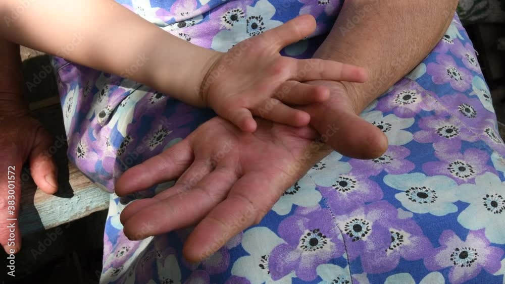 Elder woman touch and turn child hand by her wrinkled aged hands. Grandmother clap little hand of her grandchild small girl. Diverse hands of 4 year old and 80 year old Elder woman touch and turn child hand by her wrinkled aged hands. Grandmother clap little hand of her grandchild small girl. Diverse hands of 4 year old and 80 year old