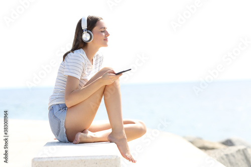 Relaxed woman with long legs listening to music on the beach