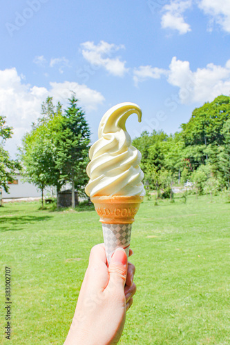 青空と緑が背景のソフトクリーム
