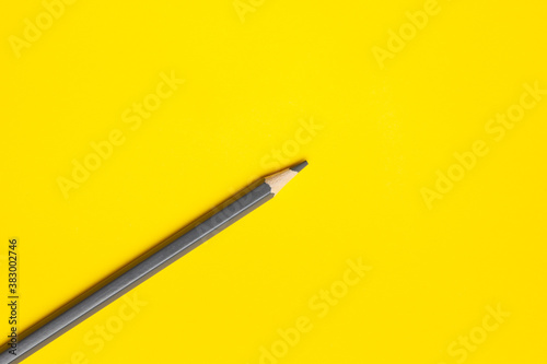 diagonal gray sharp wooden pencil on a bright yellow background, isolated, copy space, mock up.