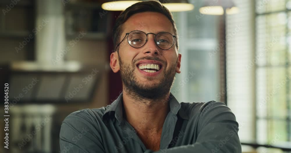 Portrait of an young self confident happy man with glasses is smiling in camera in a living room at home. Portrait of an young self confident happy man with glasses is smiling in camera in a living room at home.