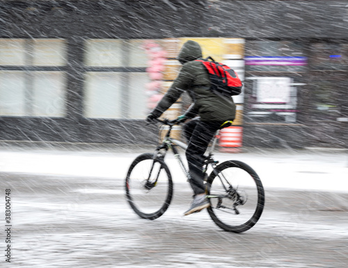 Man on bicycle in the city in snowy winter day. Intentional motion blur. Defocused image
