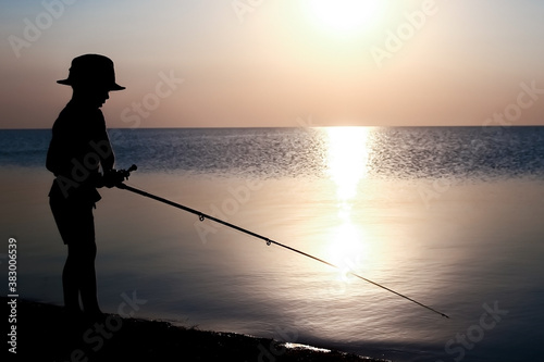 A Happy child fisherman fishing by the sea on nature silhouette travel