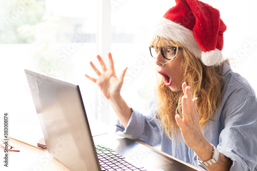 business woman in office with computer and santa claus hat surprised