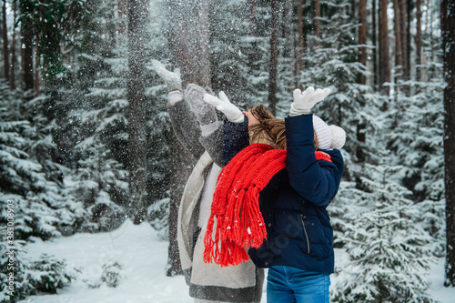 Beautiful young blonde with her charming daughter enjoy the snow outside the city in the forest.