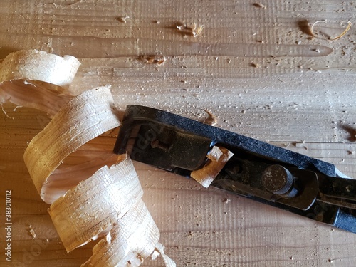 a wood plane with a big curl of wood on a wood background