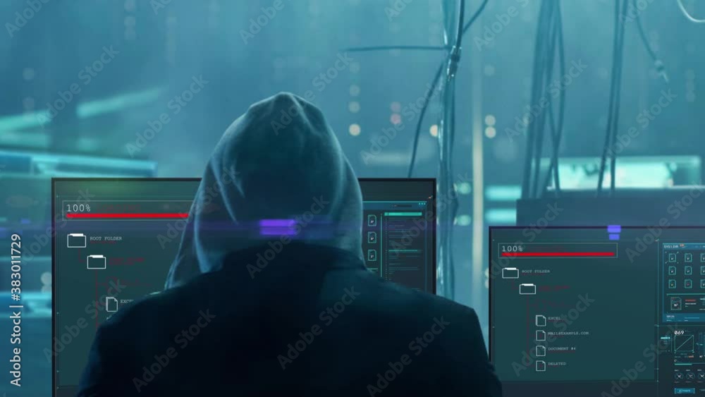 Hacker man sits with his back against the background of working computer screens.