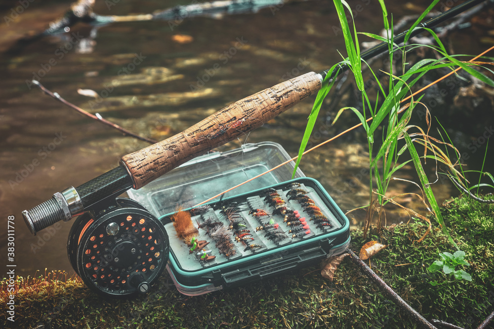 Fly rod and fly box on the bank of the stream. Stock Photo