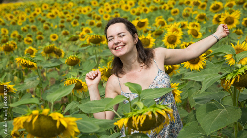 Young positive girl posing in sunflowers field and having fun