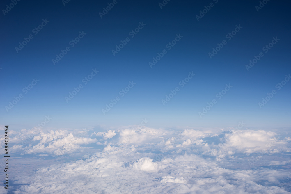 View from a window of plane with a blue cloudy sky background