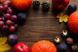 Autumn composition with seasonal products. Pumpkins, grapes, figs, apples, pine cones, walnuts, and maple leaves. Autumn mood concept, Thanksgiving concept. Top view, flat lay with copy space for text