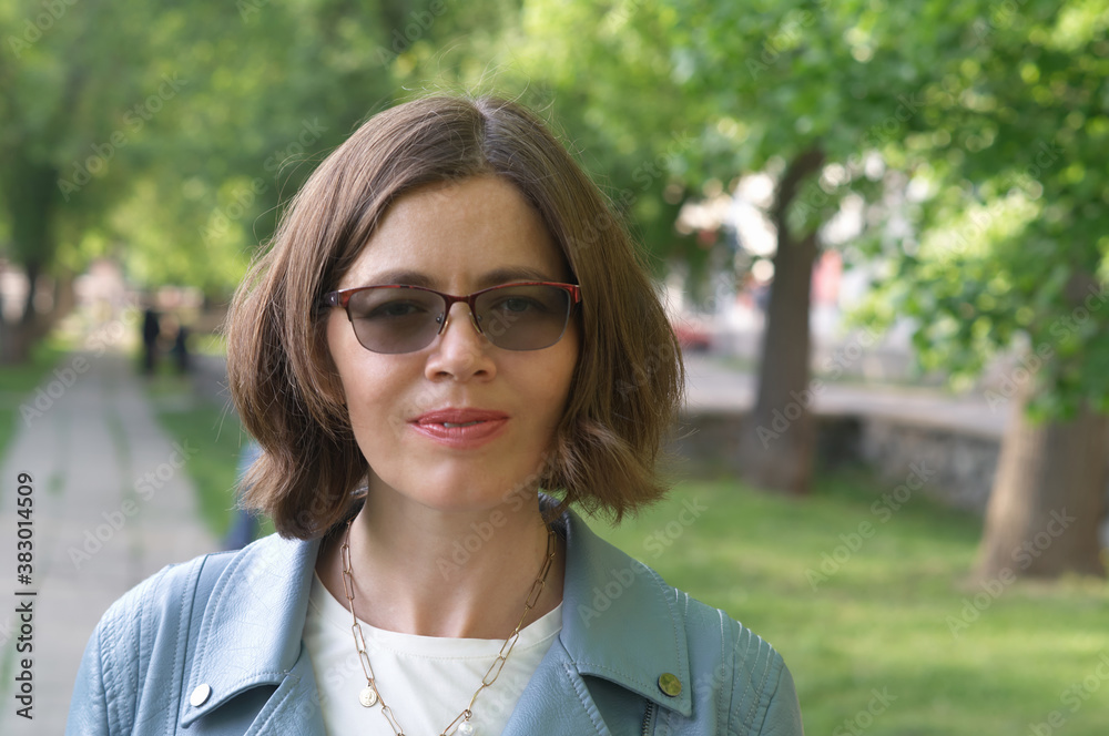 Beautiful model in blue leather jacket and glasses by spring city park Beautiful model in blue leather jacket and glasses by spring city park