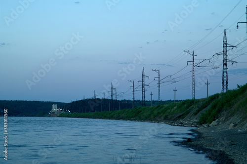 Power cable line on riverbank. Late evening on the river