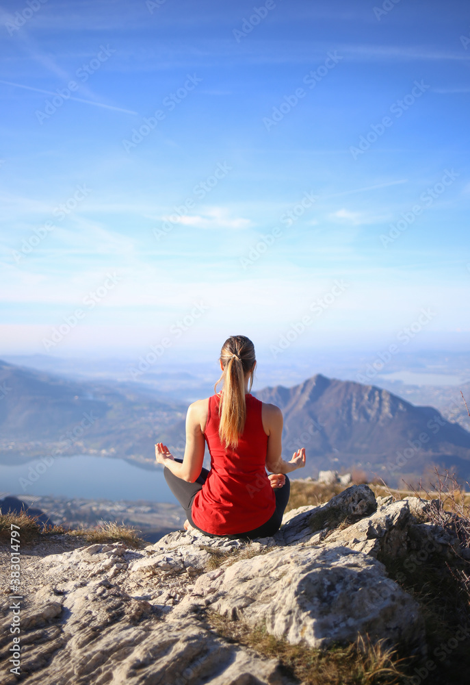 Beautiful girl meditating on top of the mountain relaxing yoga.