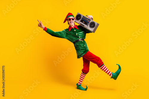 Full length body size view of his he nice attractive crazy cheerful cheery funny guy elf carrying tape player having fun dancing isolated over bright vivid shine vibrant yellow color background