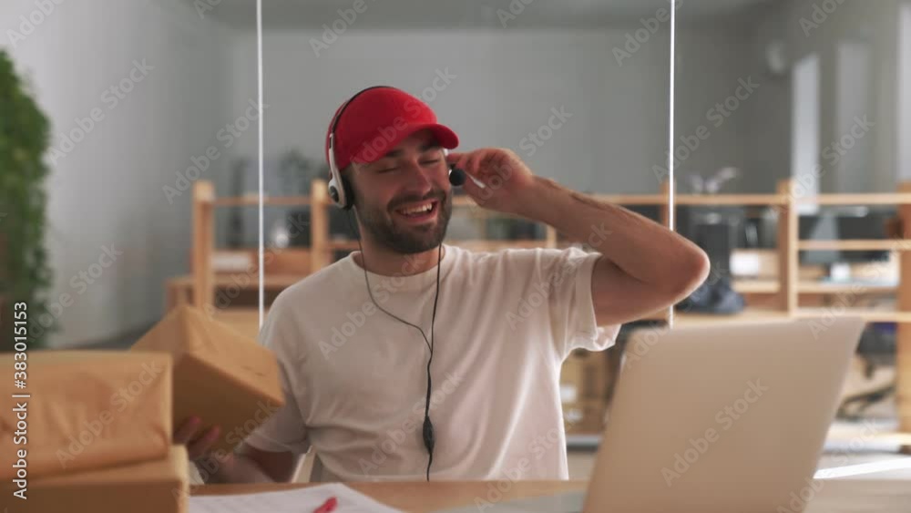 Young happy post manager indoors in office talking with client near parcel boxes Young happy post manager indoors in office talking with client near parcel boxes