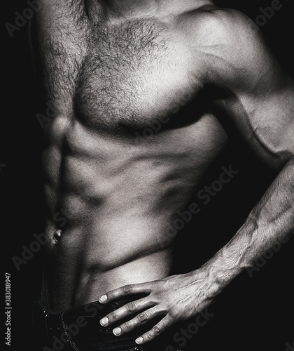 Muscular sexy man with torso. Muscular model sports young man on dark background. Sensual man with naked strong ab. Muscular torso close up. Torso concept. Black and white