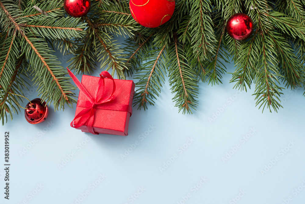Christmas tree with red decoration balls and gift box on blue background, copy space