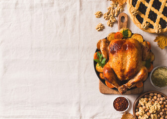Fall thanksgiving table with roasting chicken or turkey, nuts, pie, pumkins and other food on light tablecloth