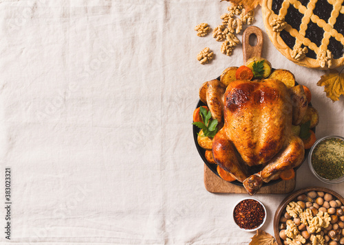 Fall thanksgiving table with roasting chicken or turkey, nuts, pie, pumkins and other food on light tablecloth