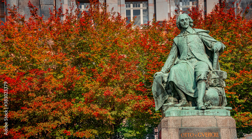 Foto Statue of great scientist Otto von Guericke in red and golden Autumn colors in historical downtown of Magdeburg Germany, at sunny day, closeup, details