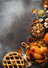 Fall thanksgiving table with roasting chicken or turkey, nuts, pie, pumkins and other food on dark background